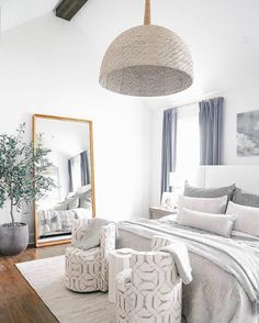 a bedroom with white walls and wood flooring is decorated in shades of gray, grey and white