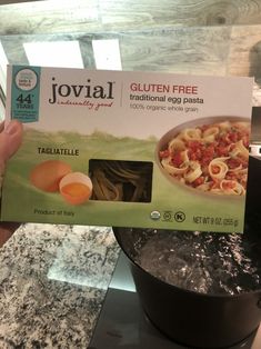 someone holding up a box of jovial gluten free pasta with an egg in it