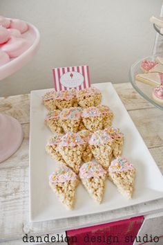 there are many desserts on the table with pink and white frosted treats in front of them