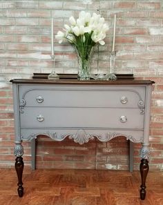 an old dresser painted gray and white with flowers on top