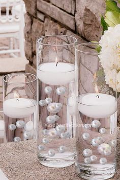 three clear glass vases filled with white candles