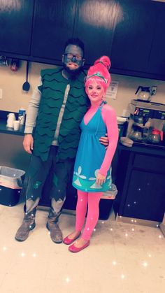 a man and woman dressed up in costumes standing next to each other on the kitchen floor