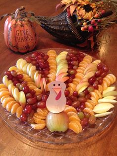 a turkey made out of pasta and grapes on top of a glass platter filled with fruit