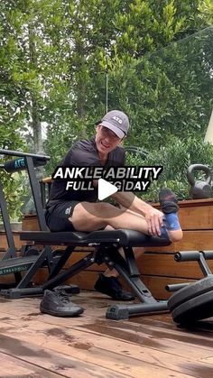 a man sitting on top of a wooden bench next to an exercise bike and water bottle