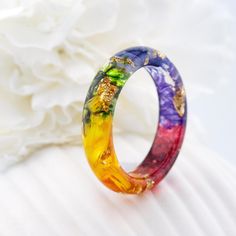 Introducing the 7 Chakra Rainbow Ring. Materials: yellow and orange marigold, green moss. geranium, cornflower, iris, purple immortelle, Gold24K Each chakra has its own color, all 7 colors are collected in the ring. Purple color develops wisdom and gives inspiration! Blue develops eloquence and intelligence! Green harmony and spiritual growth! Yellow develops will! Orange shapes feelings and emotions! Red color gives protection! Custom orders are welcome. Every item comes in a beautiful, individ Unique Rainbow Colored Rings As Gift, Unique Rainbow Rings As Gift, Unique Rainbow Rings For Gifts, Multicolor Flower-shaped Anniversary Rings, Multicolor Flower Ring As Gift, Multicolor Flower Ring Gift, Multicolor Flower-shaped Wedding Rings, Multicolor Flower Ring As A Gift, Multicolor Flower Ring For Gift