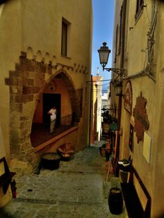 an alley way with people sitting on the steps and looking at something in the distance