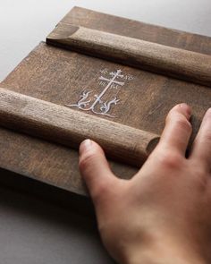 a person is holding onto a wooden plaque with an anchor and cross etched on it