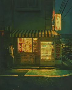 a man standing in front of a kiosk on a city street at night