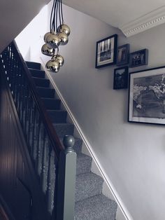 a staircase with pictures on the wall above it and hanging ornaments over the banister