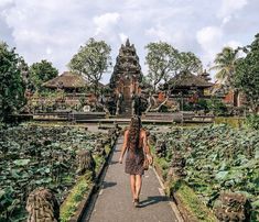 a woman walking down a path in front of a temple