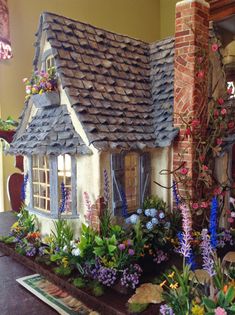 a house made out of clay with flowers around it