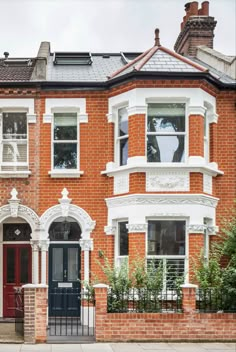 a red brick house with white trim and black gate in front of the entrance to it