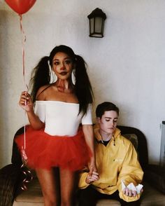 a man sitting next to a woman in a red tutu and holding a balloon