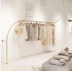 a clothing rack with clothes hanging from it's hooks in a white room next to a bench