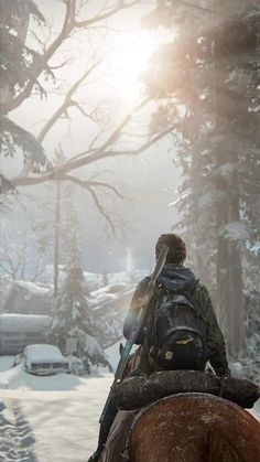 a man riding on the back of a brown horse down a snow covered forest road