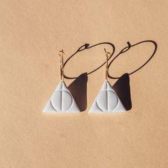 two white triangle shaped earrings on a brown surface