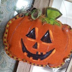 an orange pumpkin hanging from the side of a door with a green bow on it