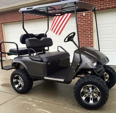 a black golf cart parked in front of a brick building with an american flag on it