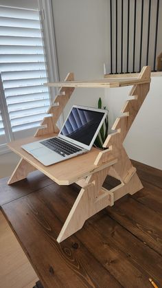 a laptop computer sitting on top of a wooden desk with a folding table underneath it