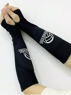 the arm sleeves are black and have white logos on them, while one hand is holding another