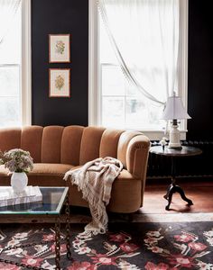 a living room filled with furniture and windows covered in white draping next to a coffee table