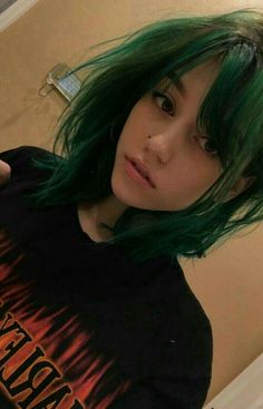 a woman with green hair is taking a selfie in front of the camera and wearing a black t - shirt