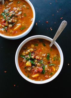 two bowls filled with soup on top of a black table next to another bowl full of soup