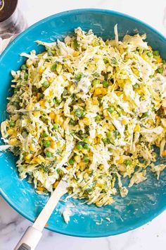 a blue bowl filled with coleslaw and corn on top of a white counter