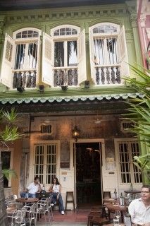 people sitting at tables in front of a building with green and white paint on it