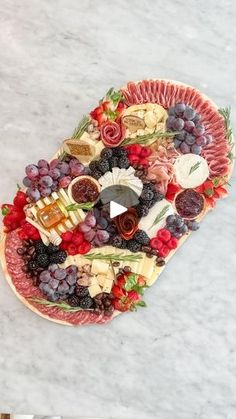 a platter filled with cheese, fruit and meats on top of a marble counter