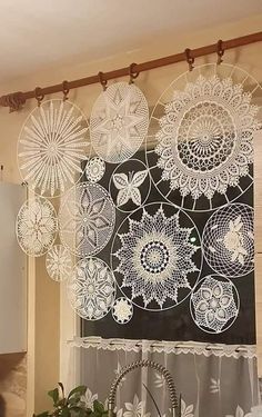 a kitchen window with lace doily hanging from it's valance, and a potted plant in front of the window