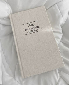 the five - minute journal journal is laying on top of a white bed sheet with black lettering