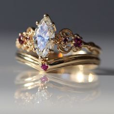 two gold wedding rings with an oval cut diamond surrounded by rubish garnets