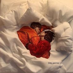 two people laying on top of a bed covered in white sheets and orange blanketing