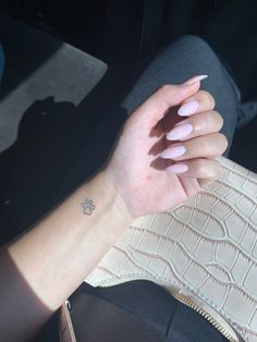 a woman's hand with pink manicures on her left wrist, and a white purse in the background