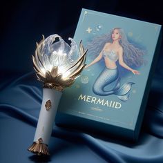 a white vase with a mermaid on it next to a blue box and an ornament