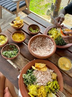 people are sitting at a table with plates of food on it and bowls of vegetables