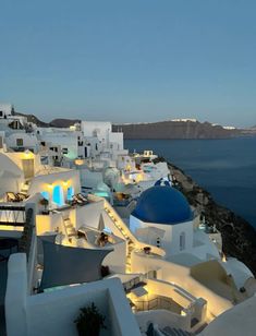 the white buildings are lit up at night by the water's edge with blue domes