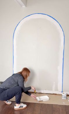 a woman is painting the wall with blue tape