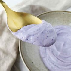 a spoon full of blueberry yogurt sitting on top of a bowl