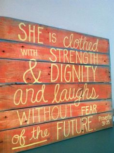 a wooden sign that says she is clothed with strength and dignify and laughs without fear