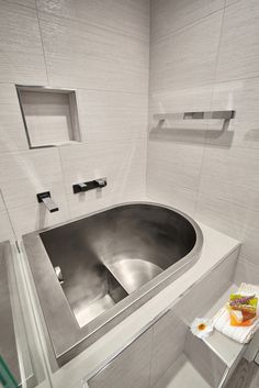 a stainless steel sink in a bathroom with white tile walls and flooring on the wall