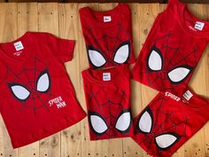 three children's spider - man t - shirts and pants on a wooden floor