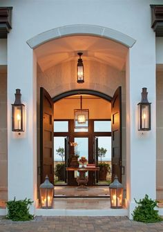 an open door leading into a home with lights on the front and side windows above it