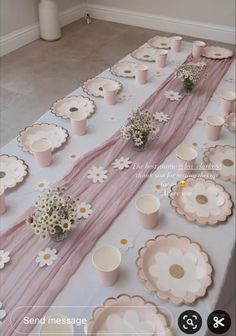 the table is set up with pink and white plates, cups, and napkins