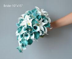 a bride's bouquet with blue and white flowers is held up against a gray wall