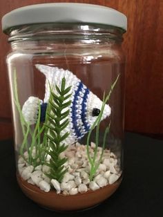 a fish in a jar with rocks and plants