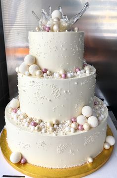 a three tiered cake with white frosting and pearls