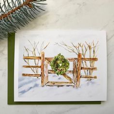 a card with a watercolor painting of a wooden gate and a wreath on it