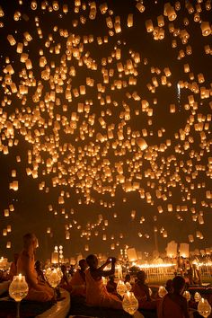 people are sitting on the ground and floating lanterns in the sky with words happy birthday